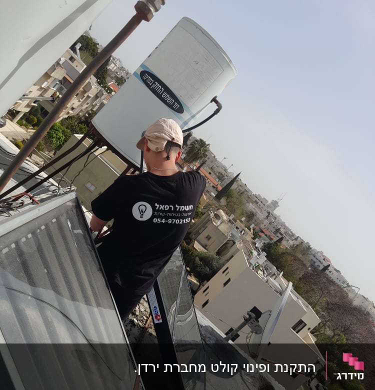 אדם עובד על דוד שמש על גג בניין